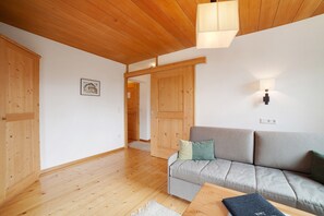 A wooden-paneled room with a sofa, a table, and a wall-mounted light fixture.