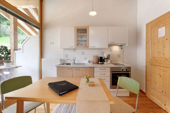 Una cocina moderna con armarios blancos, encimera de madera, una mesa de comedor con sillas y vistas al exterior.
