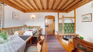 A room with a wooden ceiling, a dining table with chairs, a bench, a bed, and a green storage unit. - Apartment "Zwick Valmeina" with Panoramic Views, Balcony & Shared Garden (Mals)