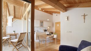 A modern interior with wooden beams, a dining area, kitchen, and a blue sofa. - Apartment "Zwick Valmeina" with Panoramic Views, Balcony & Shared Garden (Mals)