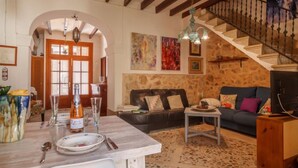 A cozy living room with a stone wall, a staircase, and a dining area with a table set for two.