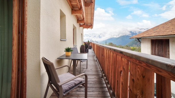 A wooden deck with a table and chairs, a potted plant, and a view of mountains. - Holiday Apartment "Zwick Spinei" with Mountain View, Balcony & Shared Garden (Mals)
