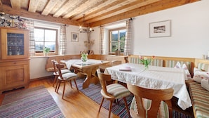 A wooden interior with a dining table, chairs, a bench, and a window with curtains. - Holiday Apartment "Zwick Spinei" with Mountain View, Balcony & Shared Garden (Mals)
