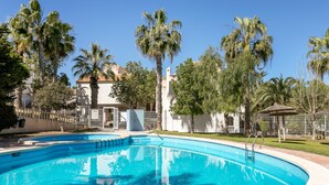 Una piscina circondata da palme e da un edificio con tetto in tegole.