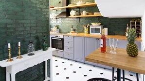 A kitchen with green brick walls, white cabinets, and a wooden countertop. There is a microwave, a stove, and a wine bottle on the counter. - Jardines de Nerja by Interhome (Nerja)