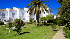 A courtyard with white buildings, a palm tree, and a stone pathway. - Jardines de Nerja by Interhome (Nerja)