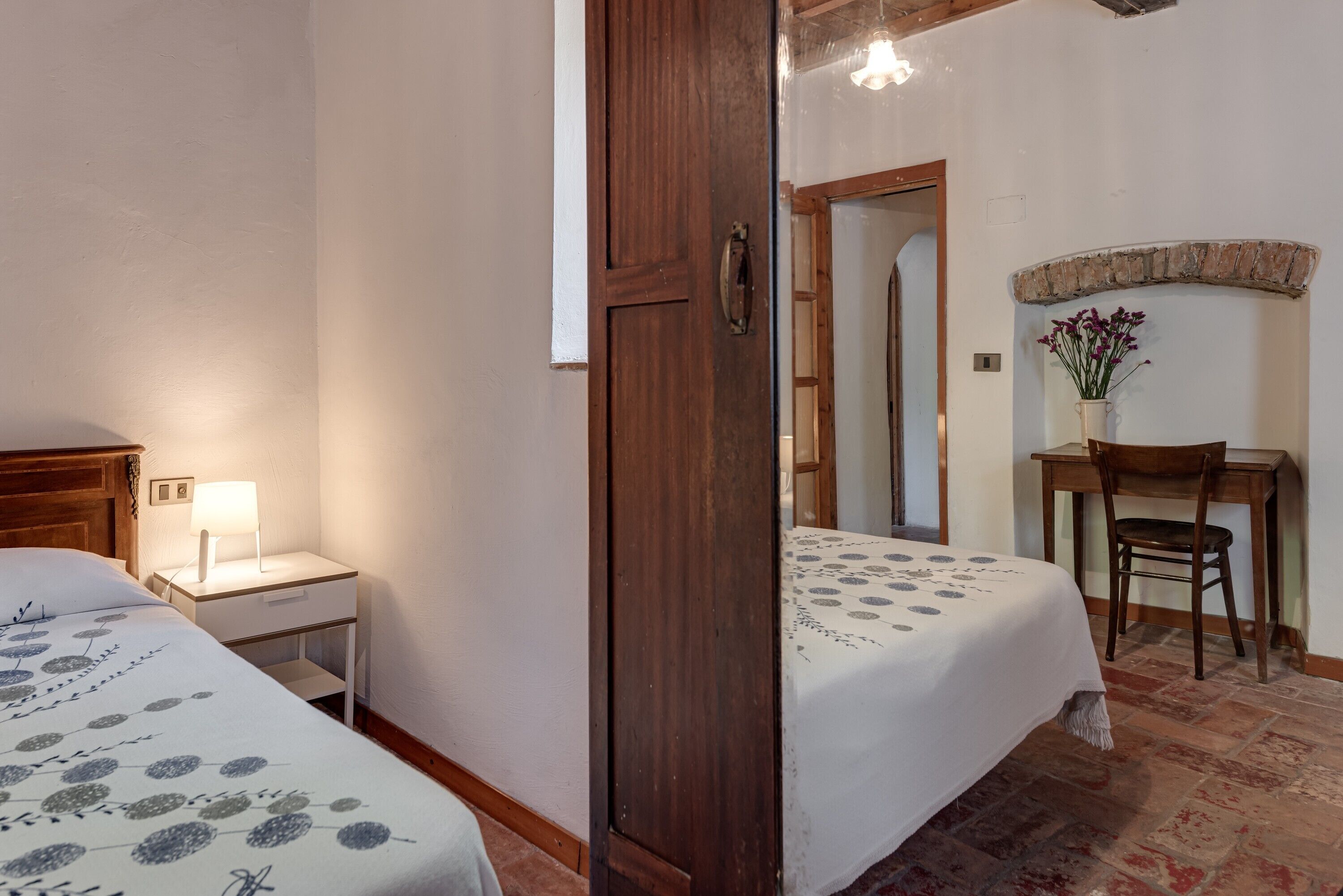 Une chambre avec deux lits, un bureau, une chaise, une lampe et un miroir.