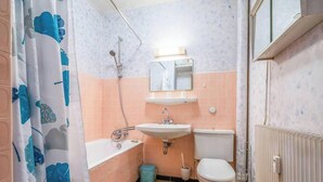 A bathroom with a shower, sink, toilet, and a mirror.