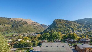 A mountainous landscape with a village, traditional wooden houses, and a clear sky.