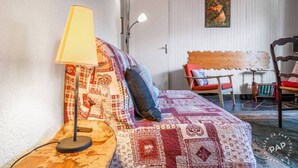 A cozy room with a bed, a lamp, a chair, and a painting on the wall.