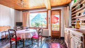 A dining area with a round table, chairs, a television, and a view of a mountain through a window.
