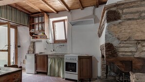 Une cuisine rustique avec des meubles en bois, un poêle blanc et une cheminée en pierre.