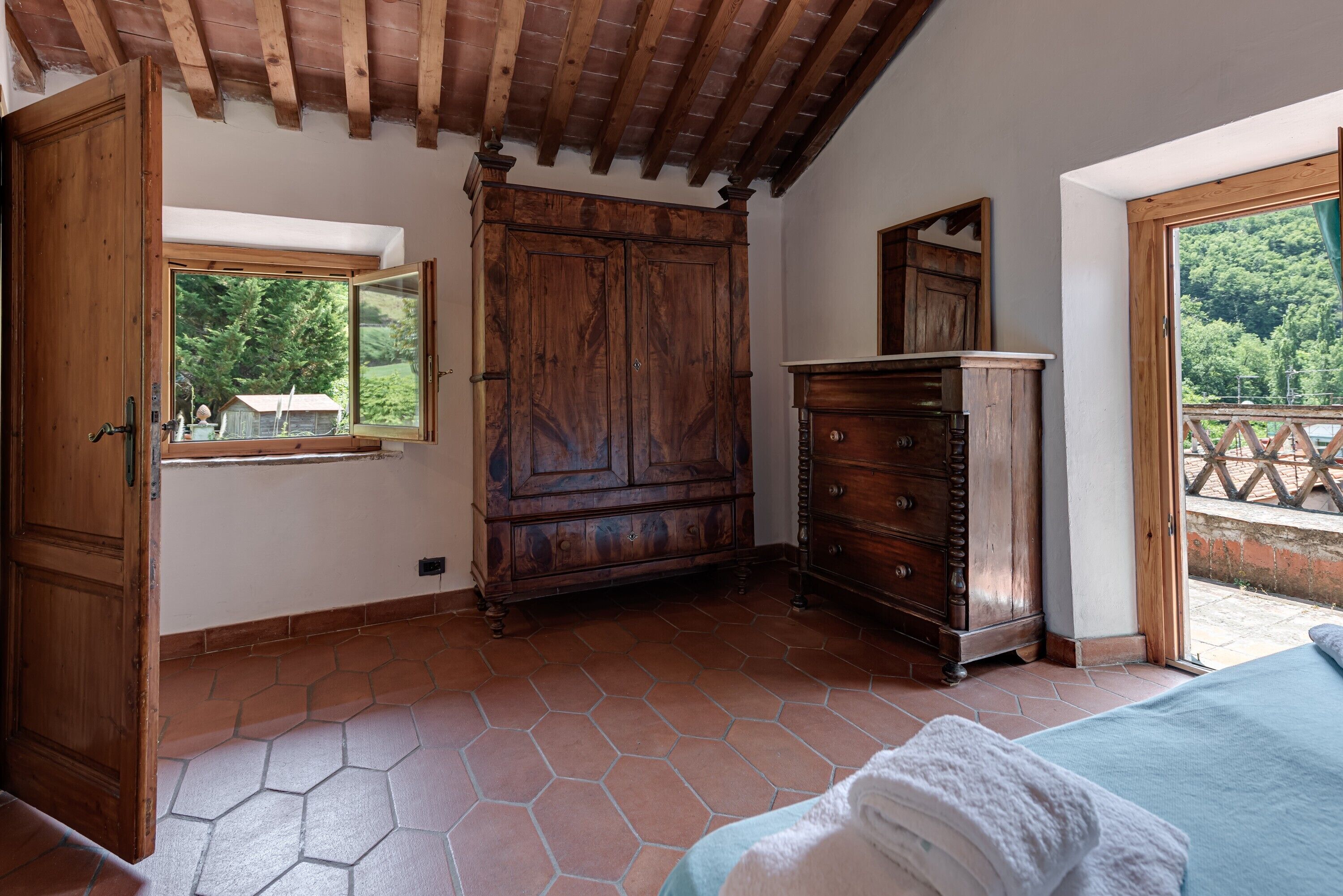 Une chambre avec une armoire en bois, un grand miroir et un lit doté d’une tête de lit bleue.