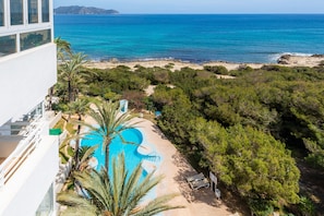 Une piscine au design original, avec vue sur la plage et entourée d’un paysage verdoyant luxuriant.