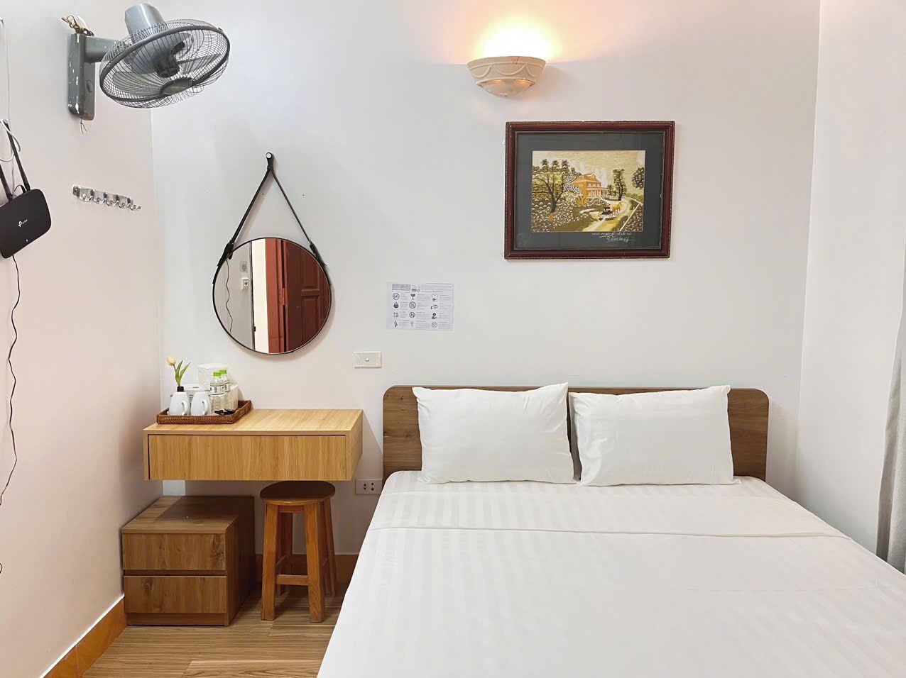 A neatly arranged bedroom with a bed, bedside table, and a mirror.