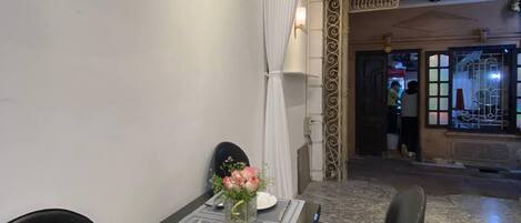 A dining area with a table set for two, a vase of flowers, and a decorative archway in the background.
