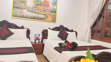 Habitación de hotel con dos camas, un cuadro de un paisaje y un ramo de flores sobre la cama.