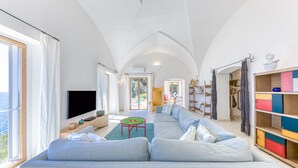 Un salón amplio con un sofá grande, un televisor de pantalla plana y un mueble de almacenamiento colorido.