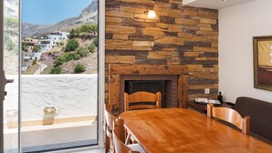 Ein Essbereich mit Kamin aus Stein, einem Holztisch und Stühlen.