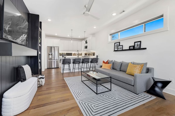 A modern living room with a sofa, coffee table, and a view of the kitchen.