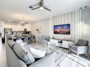 A modern living room with a sofa, coffee table, and a flat-screen TV mounted on the wall.