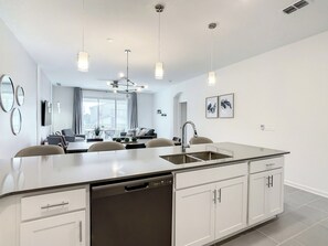 A modern kitchen with a central island, built-in dishwasher, and a dining area with a view.