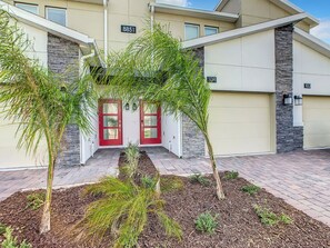 A modern building with two red doors, numbered 8851 and 104, and a stone accent wall.