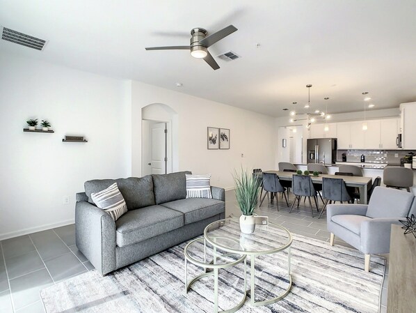 A modern living room with a gray sofa, a round coffee table, and a ceiling fan.