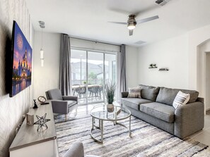 A modern living room with a grey sofa, a coffee table, and a flat-screen TV mounted on the wall.