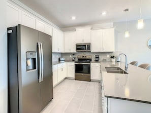 A modern kitchen with white cabinetry, stainless steel appliances, and a built-in oven.