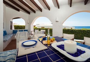 A dining area with a table set for two, a candle, and a view of the sea. - Villa 'Bini Sek' with Sea View, Private Terrace and Air Conditioning (Binibèquer)