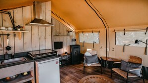 A compact kitchen with a stove, sink, and refrigerator, a dining area with a table and chairs, and a large window with a view.