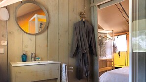 A wooden room with a bathroom, a bed, and a hanging robe.