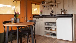 A compact kitchen with a dining area, wooden cabinets, a white refrigerator, and a hanging pot rack.