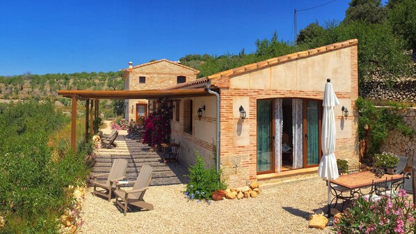 A stone building with a patio, outdoor seating, and a view of the surrounding landscape.