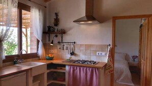 Une cuisine de taille réduite, équipée d’une cuisinière à gaz, d’un évier et d’une fenêtre avec des rideaux.