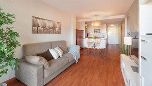 A modern living room with a sofa, a dining area, and a kitchen in the background. - Vacation Home "Vista Paraiso" with Sea View, Shared Pool & Wi-Fi (Adeje)
