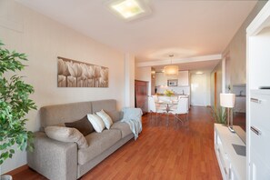 Een moderne woonkamer met een bank, een eethoek en een keuken op de achtergrond.