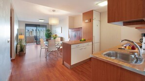 A modern kitchen with wooden cabinets, a stainless steel sink, and a dining area with a table and chairs. - Vacation Home "Vista Paraiso" with Sea View, Shared Pool & Wi-Fi (Adeje)