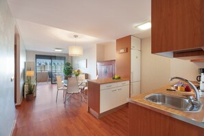 Een moderne keuken met houten kastjes, een roestvrijstalen spoelbak en een eethoek met een tafel en stoelen.