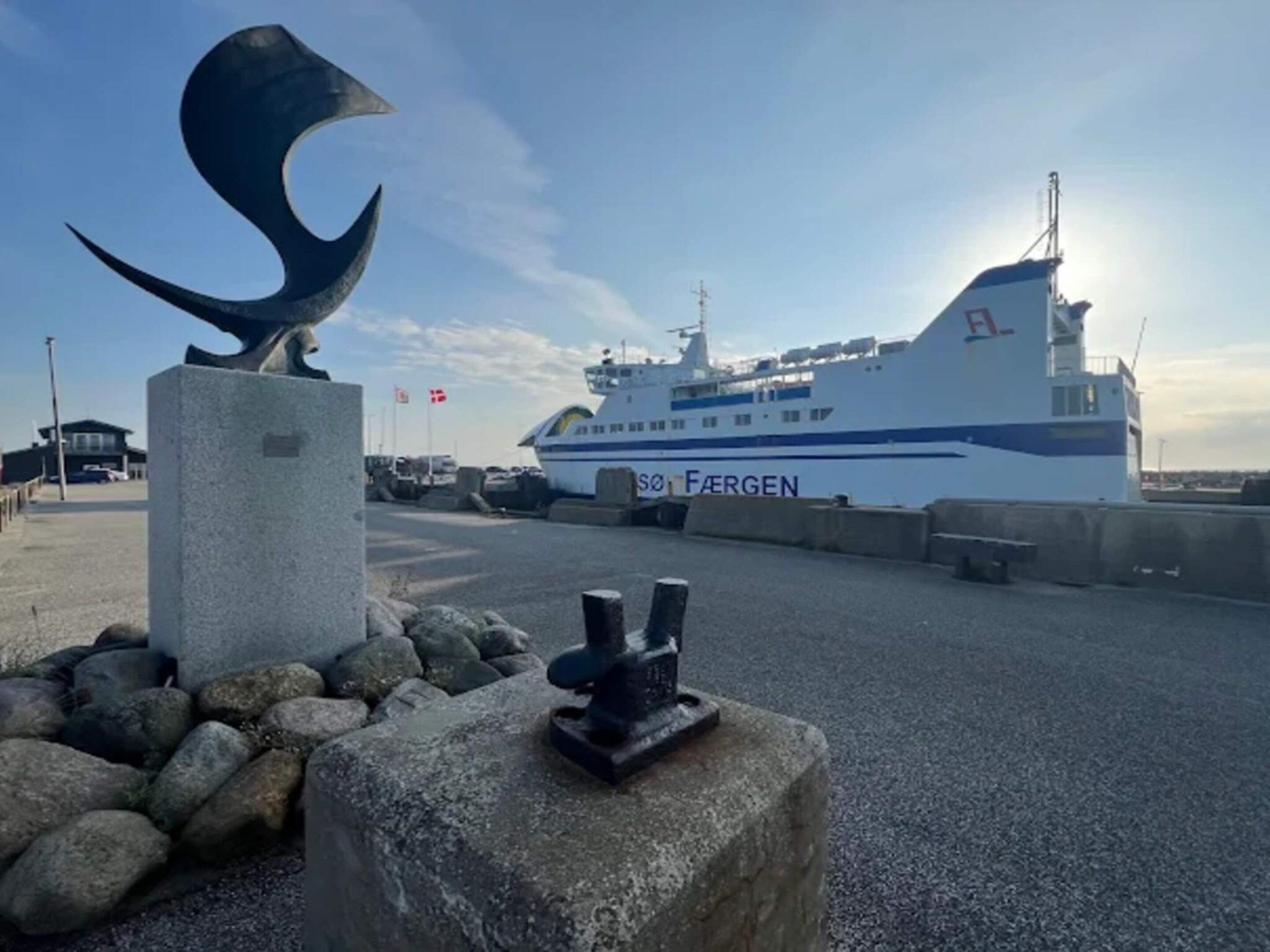 A large cruise ship docked at a port with a sculpture in the foreground.
