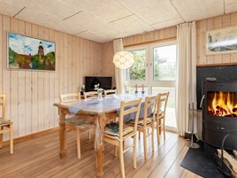 Um quarto aconchegante com decoração em madeira, uma mesa de jantar com cadeiras, lareira e televisão.