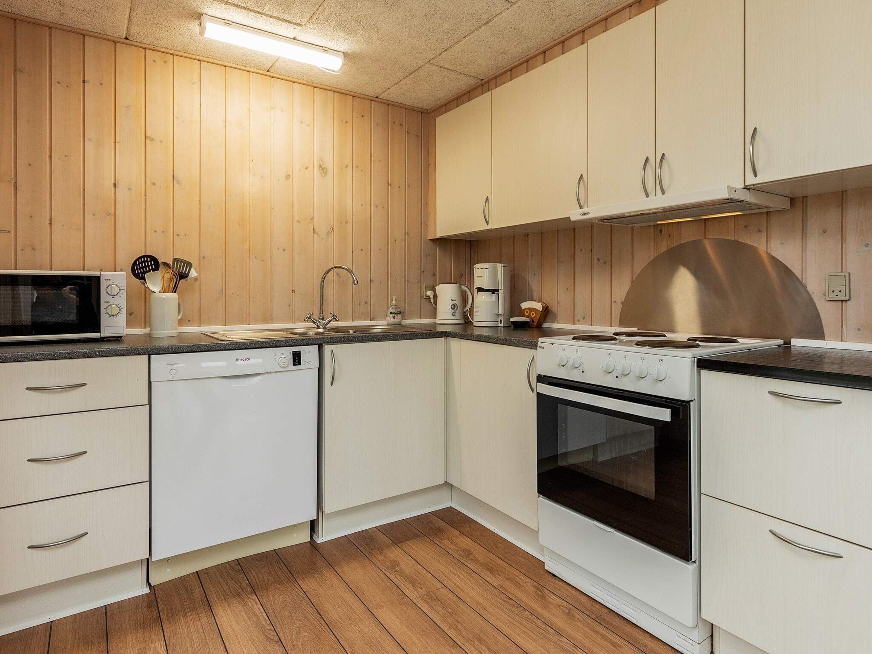 A compact kitchen with white cabinets, a microwave, a dishwasher, a stove, and a sink.