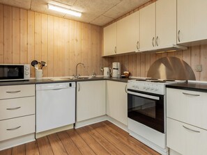 A compact kitchen with white cabinets, a microwave, a dishwasher, a stove, and a sink. - 6 Person Holiday Home in Laeso (Læsø)