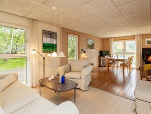A spacious living area with a sofa, a dining table, and a fireplace. - 6 Person Holiday Home in Laeso (Læsø)
