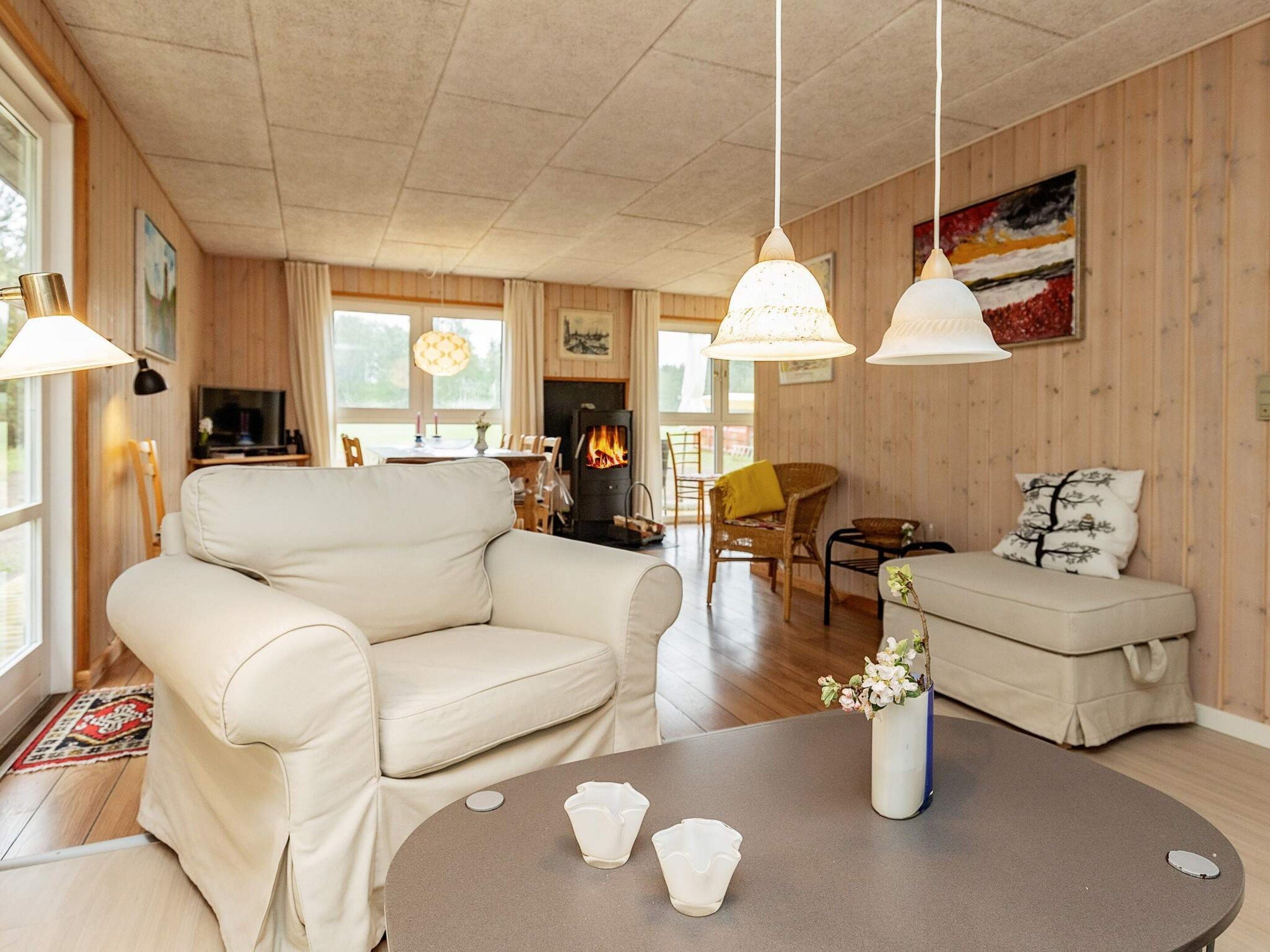 Een gezellige woonkamer met een bank, een eettafel en een open haard.
