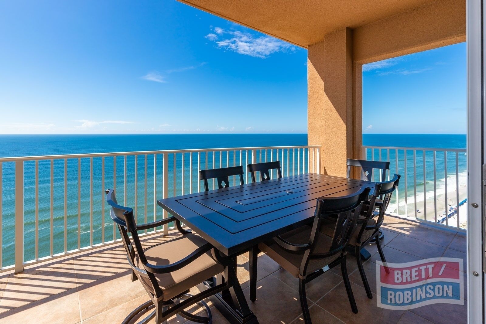 A balcony with a table and chairs overlooking the ocean.