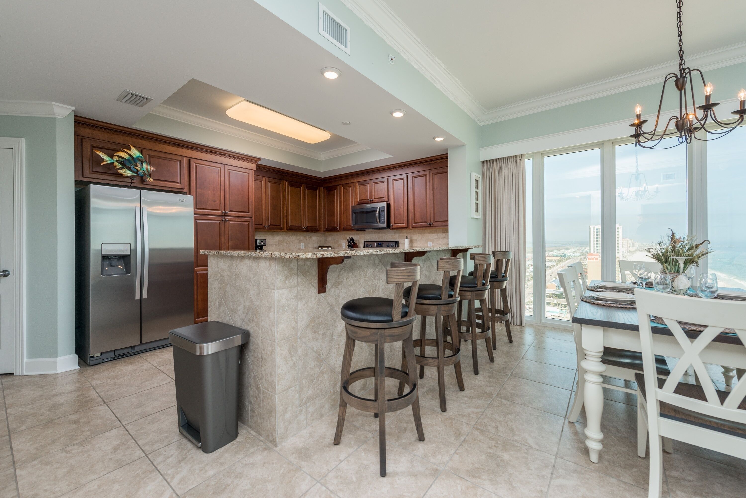 Una cocina moderna con una isla central, taburetes de bar y un comedor con vistas.
