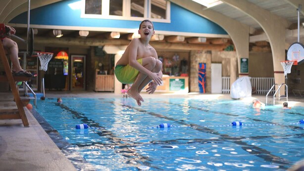 An indoor swimming pool with lanes, a basketball hoop, and a wooden deck area. - Seven Springs Stoneridge 3 Bedroom Standard Condo, Mountain Views! by RedAwning (Champion)