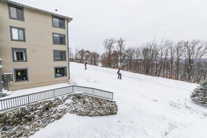 Un immeuble à plusieurs étages, doté d’un mur de soutènement en pierre et d’une pente recouverte de neige.
